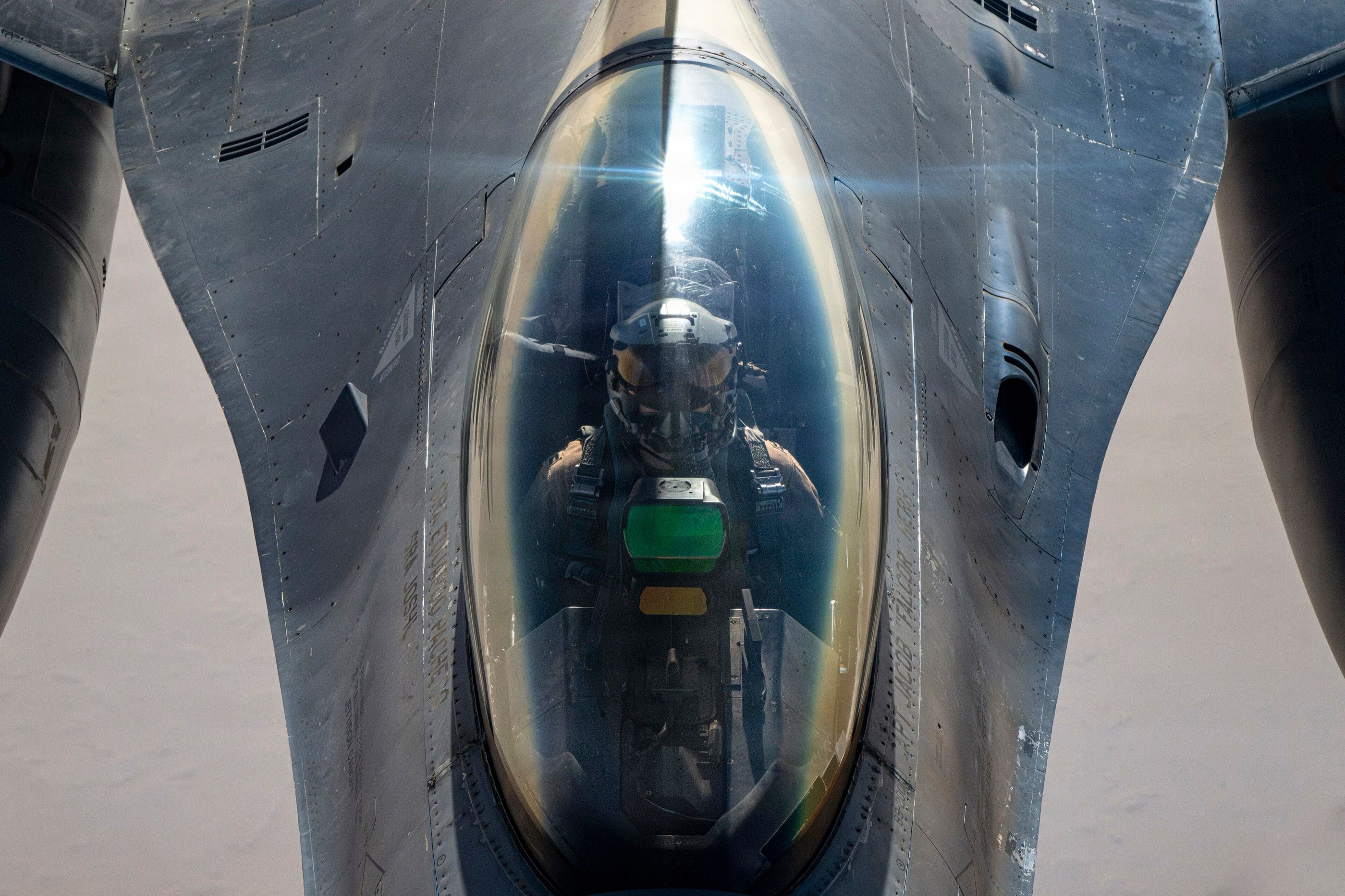 An F-16 pilot seen through the canopy, close up from the tanker's boom position